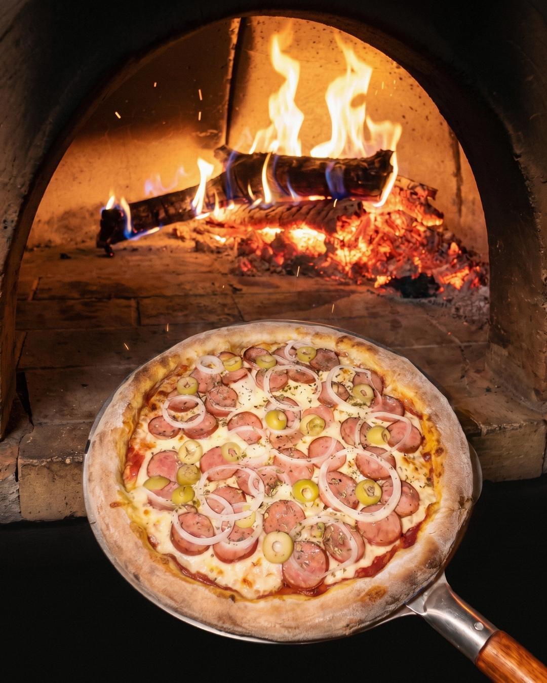 Pizza inteira saindo do forno a lenha